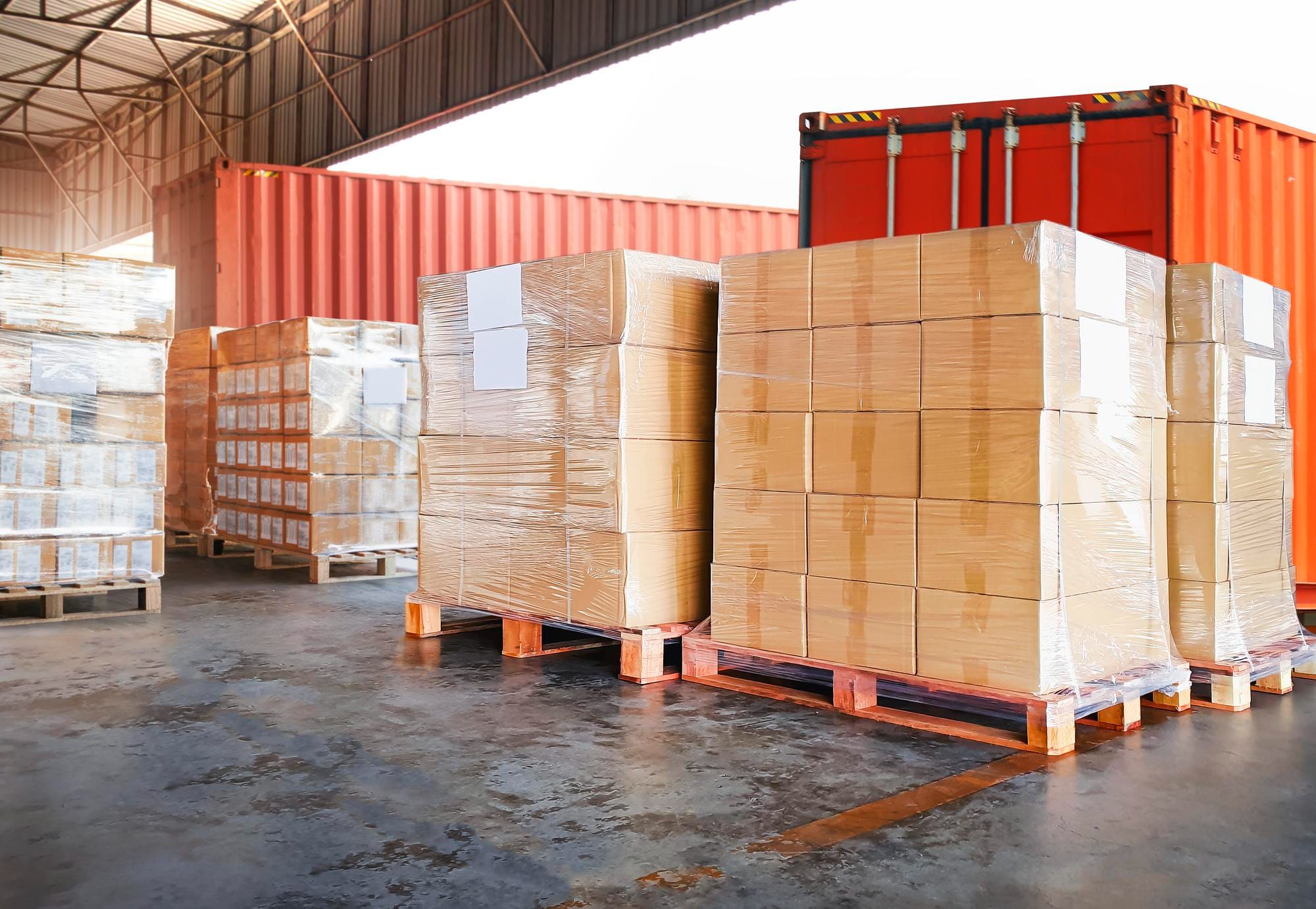 Cardboard boxes stacked on wooden pallets in a warehouse, showing pallets’ key role in efficient supply chain logistics.