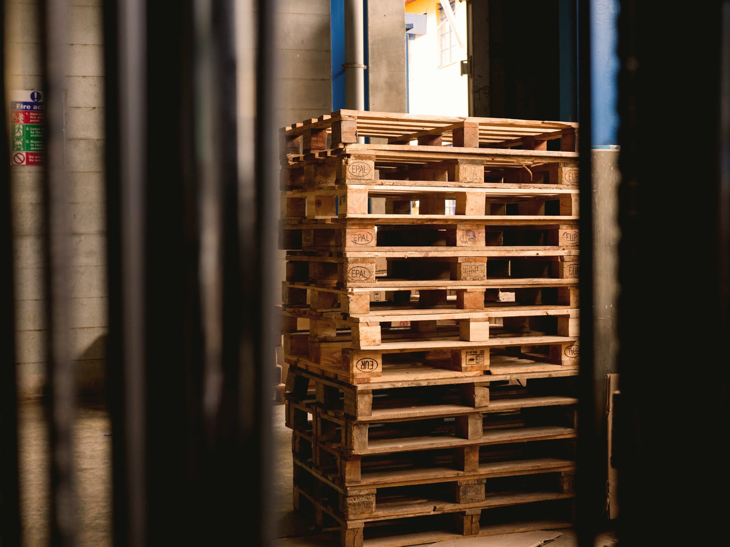 Neatly stacked wooden pallets in a warehouse storage area.