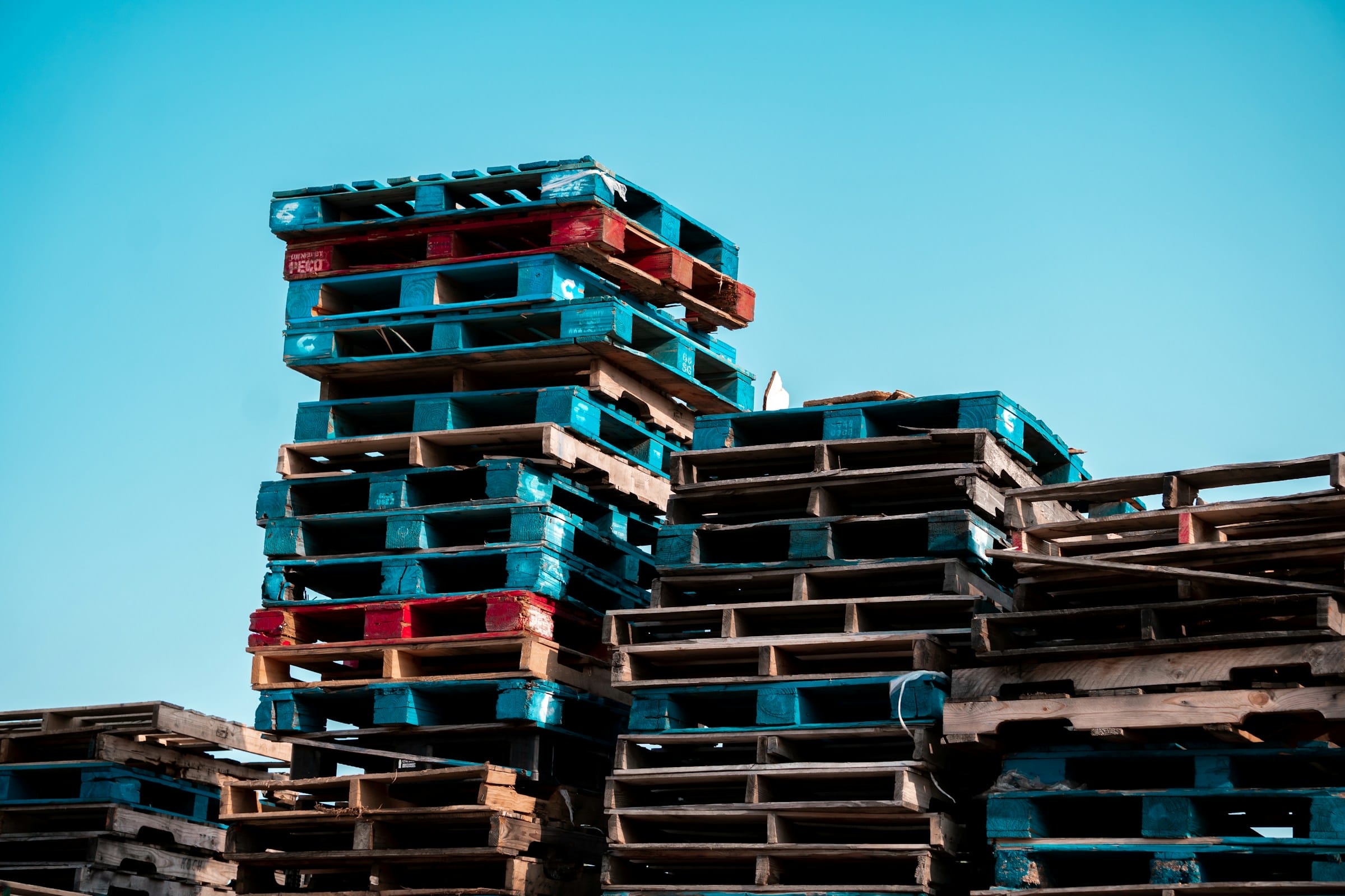 Stacked wooden pallets used in business logistics, illustrating the cost comparison between buying vs renting pallets for commercial operations