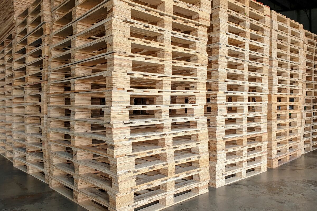 Large stacks of newly manufactured wooden pallets inside an industrial warehouse
